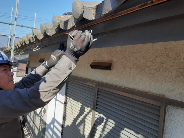 軒樋の金具を外している